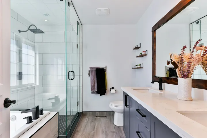 Walk-in tiled shower with glass door and white wall tile